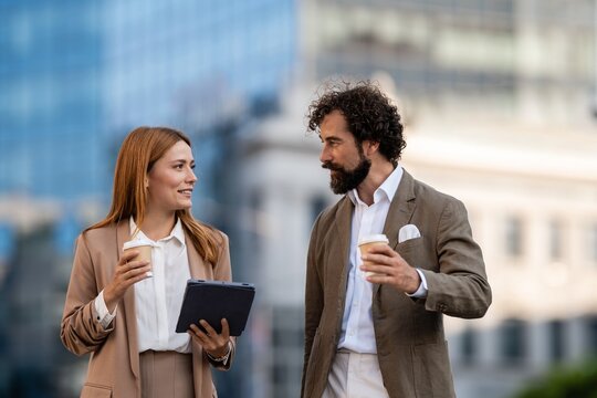 Businesspeople talking and holding coffee and tablet in the city