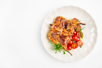 Grilled quail with cherry tomatoes and fresh herbs served on a white plate, top view copy space culinary advertising and menu design