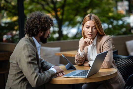 Business people working on laptop and tablet at outdoor cafe - Powered by Adobe