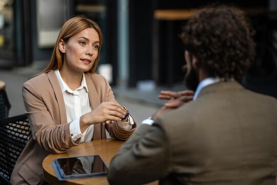 Businesswoman talking to businessman at outdoor cafe table
