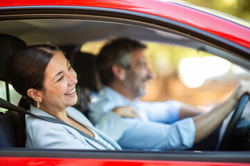 Woman smiling at driver while enjoying ride in red car