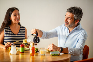 Couple preparing and enjoying coffee together at breakfast table
