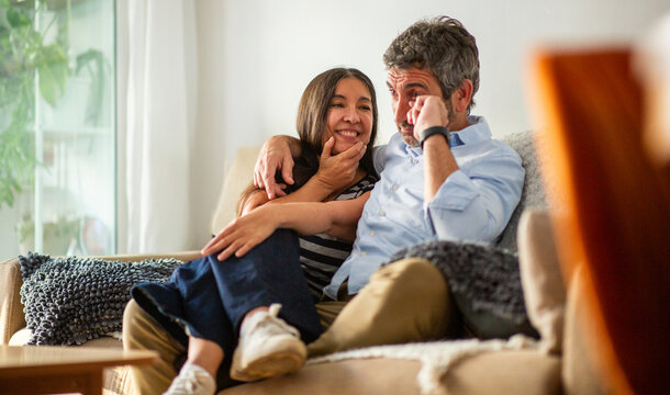 Couple watching TV with playful teasing and mixed emotions