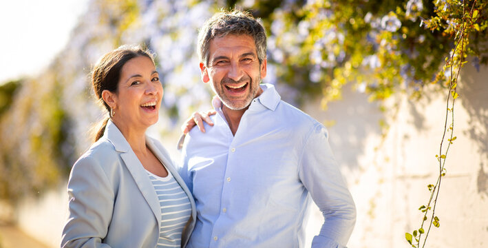 Happy middle-aged couple laughing outdoors on a sunny day