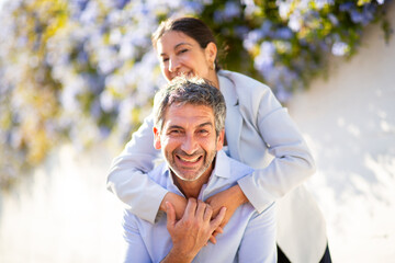 Smiling mature couple enjoying a playful piggyback ride outdoors
