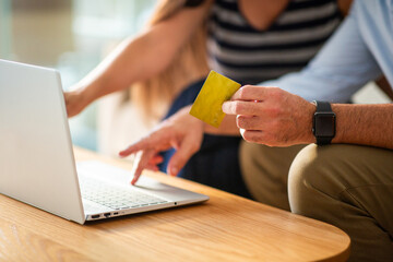 Close-up of couple using credit card for online payment at home