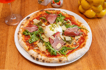 Pizza avec burrata, jambon de Parme, roquette, copeaux de parmesan et sauce pesto