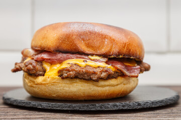Smash burger au steak, bacon et fromage cheddar sur une ardoise, gros plan
