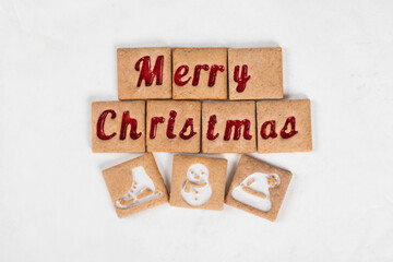 Festive square cookies with red and white marmalade filling in the shape of the words Merry Christmas and skate, snowman, hat. White background. Top view