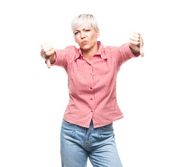 Obraz premium Displeased middle aged woman showing thumbs down, isolated on white background. Dislike or negative concept.
