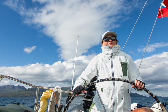 Woman sailing amidst Norway scenic fjords under blue skies