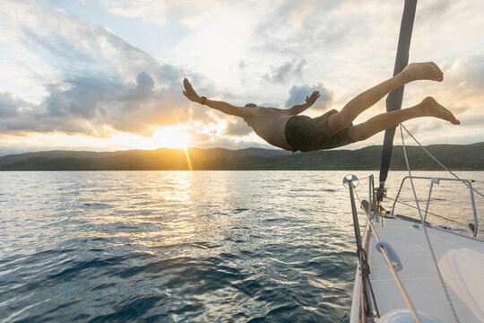 Man diving off a sailboat at sunset in the Mediterranean