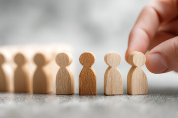 Hand selecting a wooden figure from a lineup of diverse person-shaped tokens symbolizing recruitment, leadership, and decision-making concepts in business and teamwo