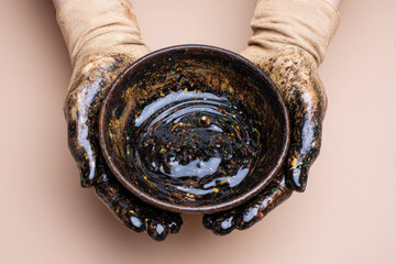 oil hands are folded in a bowl of oil. Oil spill. Environmental pollution. an environmental disaster.