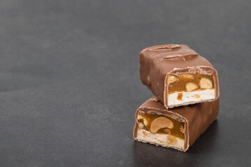 Chocolate peanut bar. With nougat and caramel. Dark background. Copy space