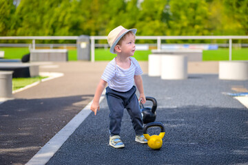 Toddler standing near kettlebells outdoors