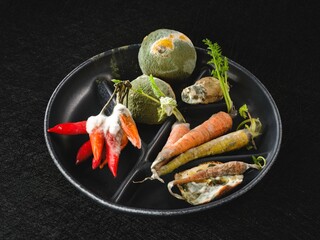 A black plate holds various discarded vegetables and spoiled herbs, highlighting the reality of food waste. This stark representation emphasizes the need for mindful consumption and reduction