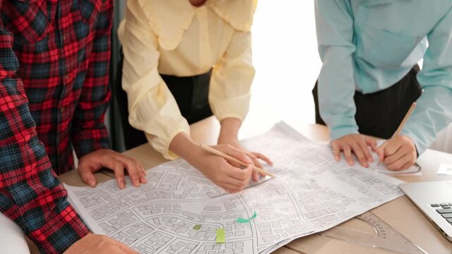 Professional engineer team discussion about house design on meeting table with architectural equipment and building blueprint scatter around at modern office. Focus on hand. Closeup. Delineation.