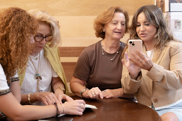 Women of different generations bonding sharing smartphone content