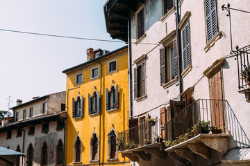 Historic buildings with shutters and balconies in Verona, Italy, on a sunny day.
