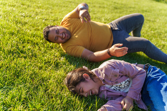 Father and daughter lying on grass in sunny park