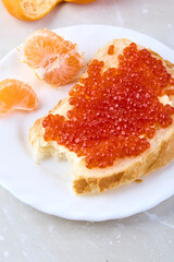 Sandwich with red caviar and tangerines. Traditional Russian treat on the New Year's table.