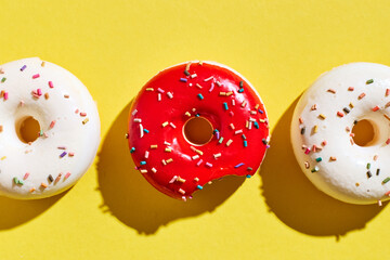 Overhead view of various donuts with confetti arranged on colored background