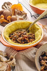 Quiche dough in a baking dish filled with mushroom filling of fried chanterelles, oyster mushrooms and champignons