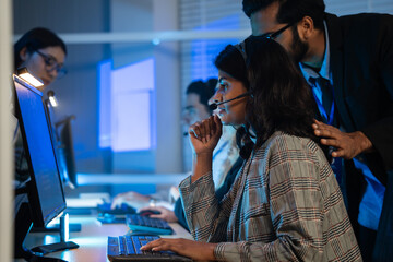 Customer service agent wearing headset working call center in a control room. Telephone support, IT helpdesk staff, teamwork overtime, telemarketing and corporate operations with corporate team
