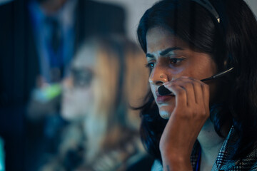 Indain female customer service or IT support agent in a headset, working late at control room or corporate call center. Technical support, BPO operations, problem-solving, telemarketing 