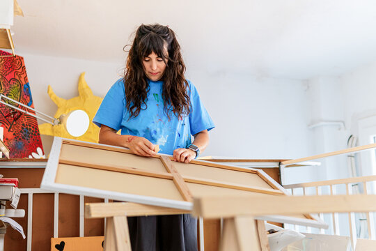 Visual artist in studio preparing a new painting canvas