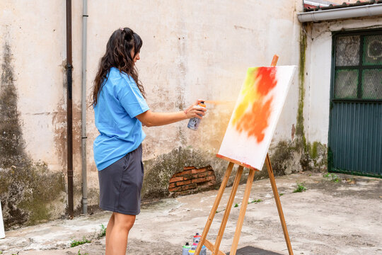 Artist applying spray paint in outdoor workshop
