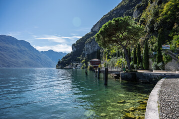View from Riva del Garda across Lake Garda toward the Ponale trail, with deep blue water, steep...