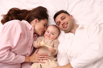 Fototapeta premium Happy parents with their cute baby on bed, top view
