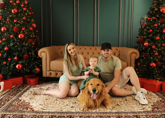 fam&iacute;lia celebra o natal com cachorro golden retriever em sala de natal 