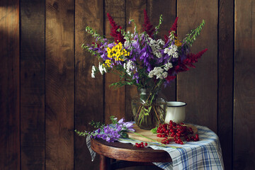 Still life featuring rustic wildflowers and red currants on a boardwalk background