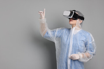 Modern technology. Doctor in headset using virtual screen on grey background. Space for text