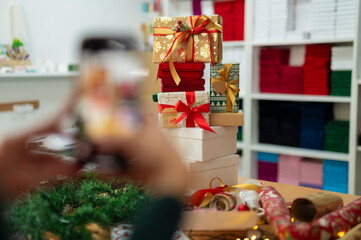 Person photographing christmas presents with smartphone for social media