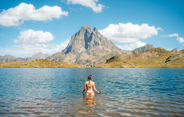 Woman in lake with mountain in background under blue sky