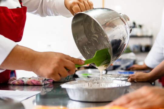 Chef hands pouring batter into baking molds