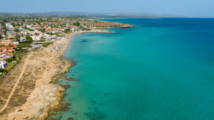 Aerial view of the sandy beach of San Lorenzo, located in the province of Syracuse, Sicily, Italy. It is a popular summer resort. There are parasols and vacationers on this coast with clear waters.