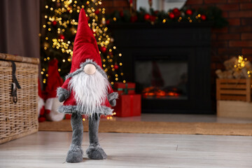 Naklejka premium Funny Christmas gnome on floor in decorated room. Space for text