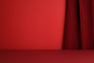 Fototapeta na wymiar Simple, empty red studio stage with a dark red pleated curtain on the right side.