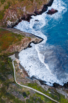 Aerial view of the rugged coastline, where turquoise waters crash against the dark, rocky cliffs near the coastal path, St. Davids, Wales, United Kingdom.