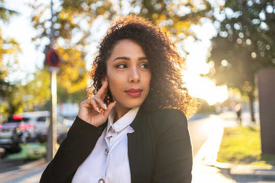 Confident businesswoman with curly hair in sunlight