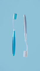 Two plastic toothbrushes on blue background with empty copy space for dental clinic services, oral hygiene education and family healthcare banner design
