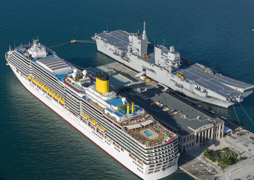 Aerial view of a cruise ship and a navy vessel docked side by side, their contrasting colors and purposes creating a striking juxtaposition, Trieste, Italy.