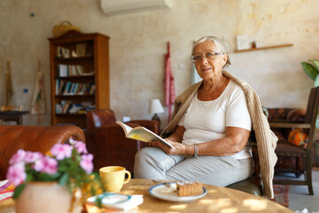 Senior woman relaxing at home reading book