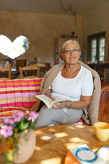 Senior woman relaxing at home reading book