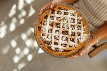 Woman holding homemade lattice apple pie with powdered sugar